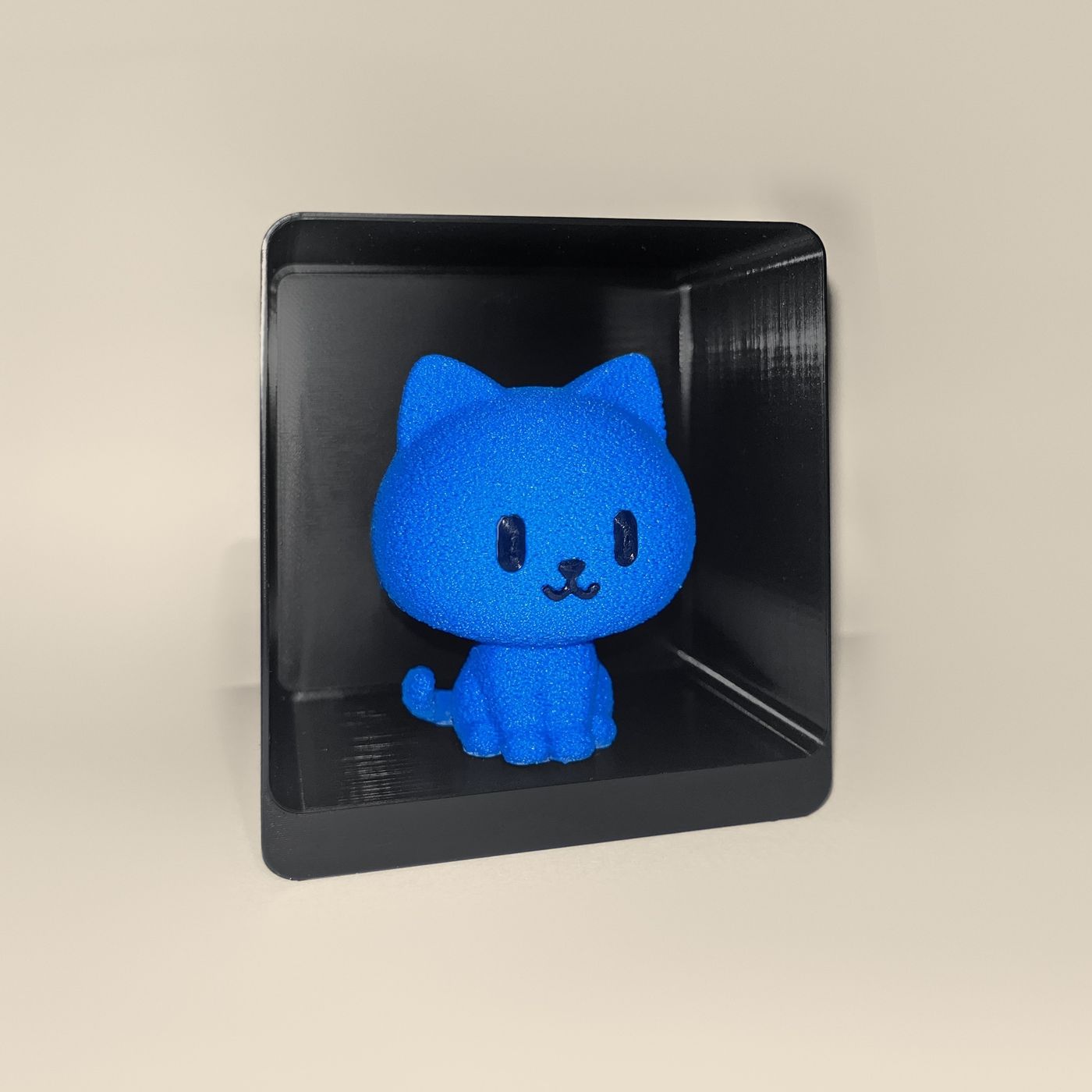 3D-printed cat figurine, angled view: a blue cat with black eyes and a smiling mouth