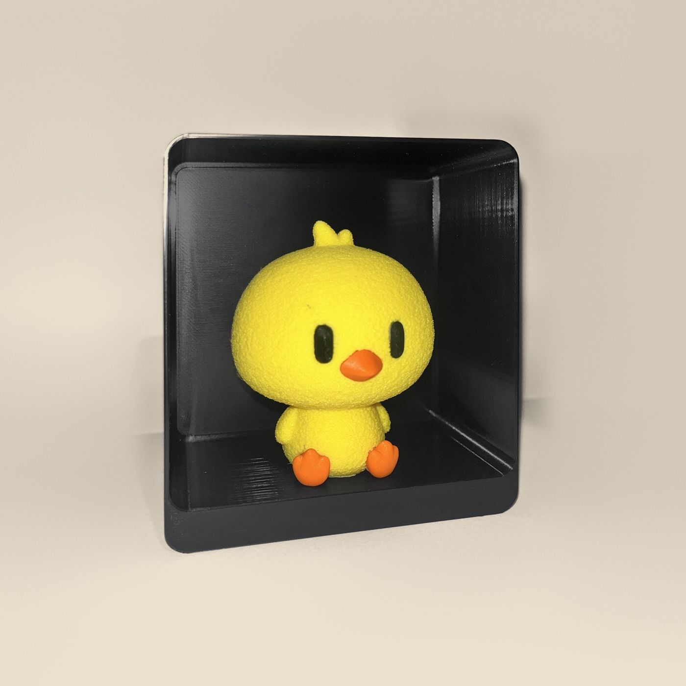 3D-printed chick figurine, angled view: a yellow chick with orange beak and feet
