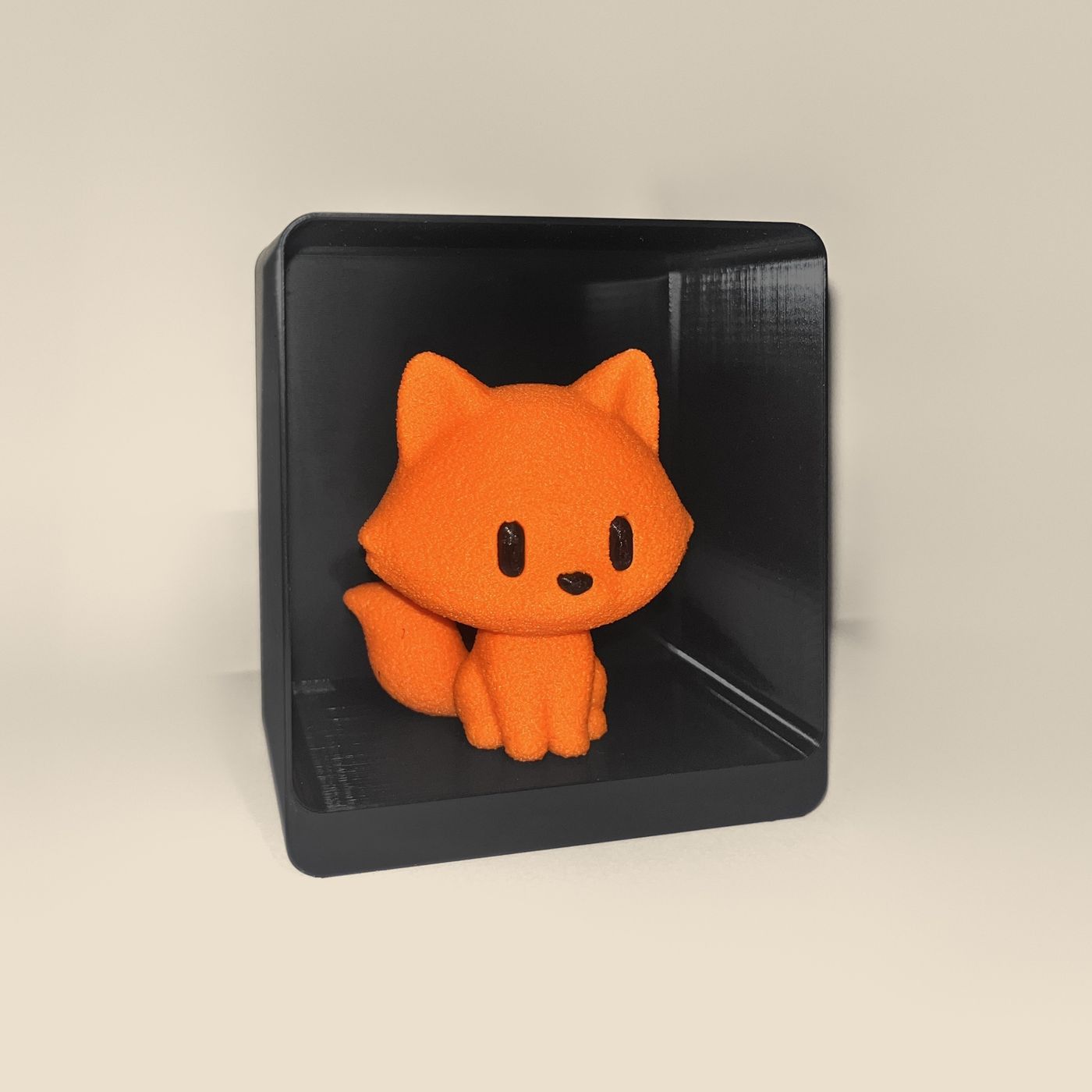 3D-printed fox figurine, angled view: an orange fox with black eyes and nose and a fluffy tail