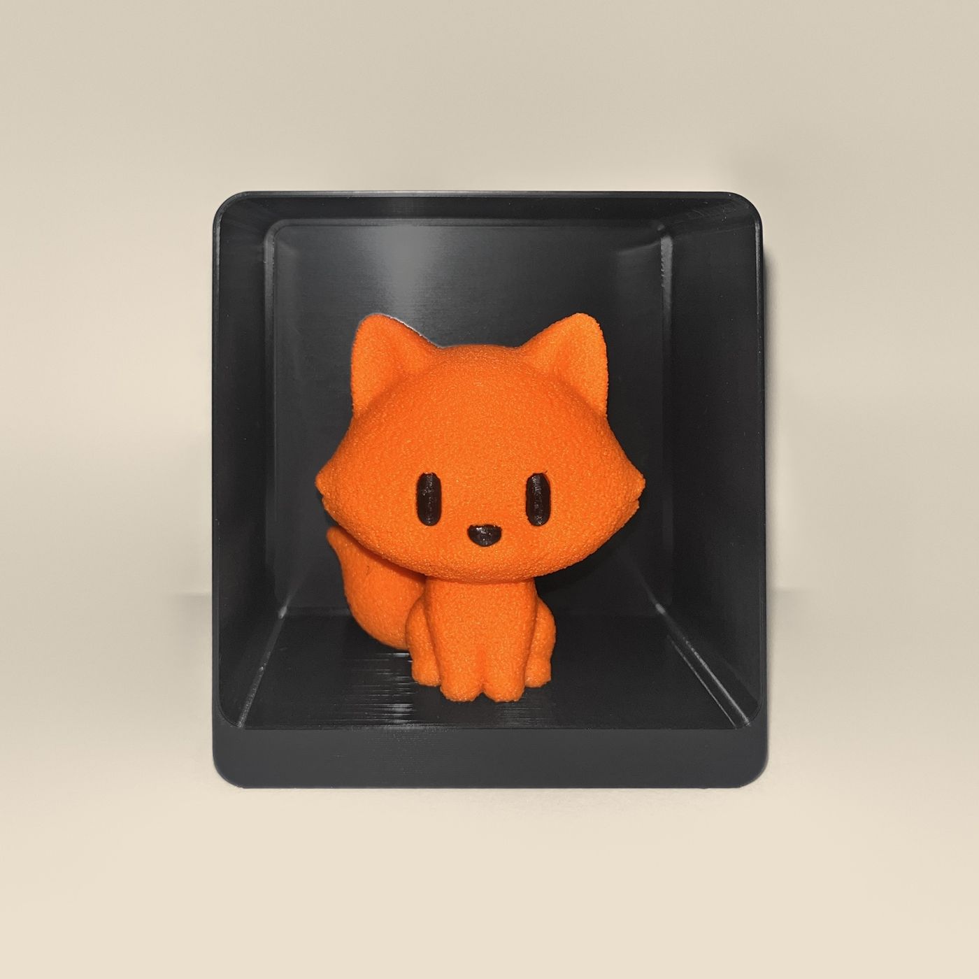 3D-printed fox figurine, front view: an orange fox with black eyes and nose and a fluffy tail