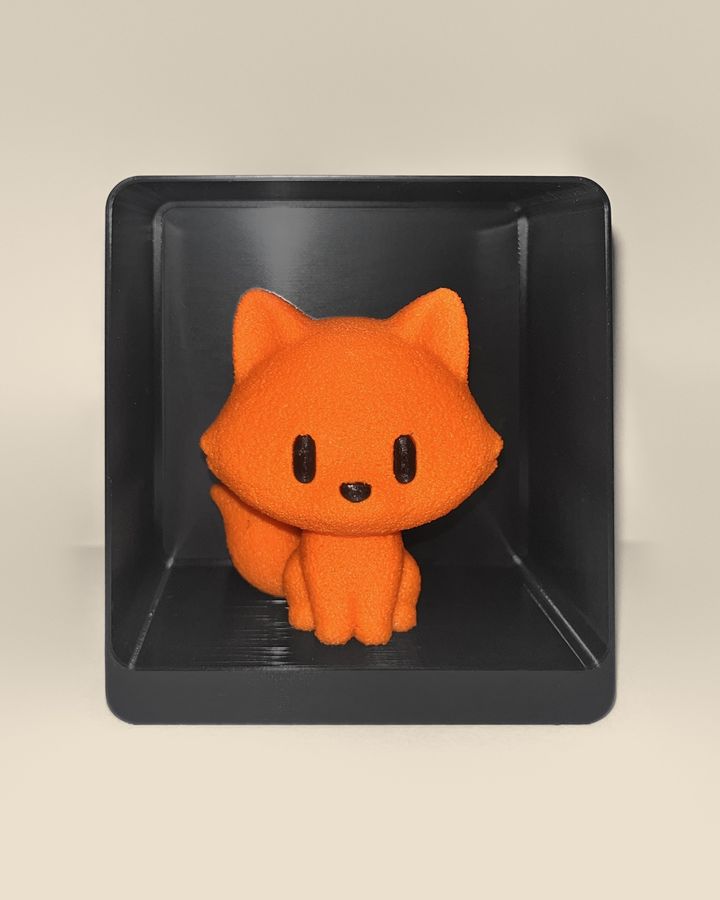 3D-printed fox figurine, front view: an orange fox with black eyes and nose and a fluffy tail