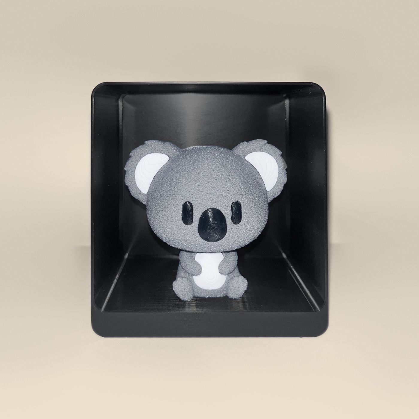 3D-printed koala figurine, front view: a grey koala with white ears and belly and a black nose