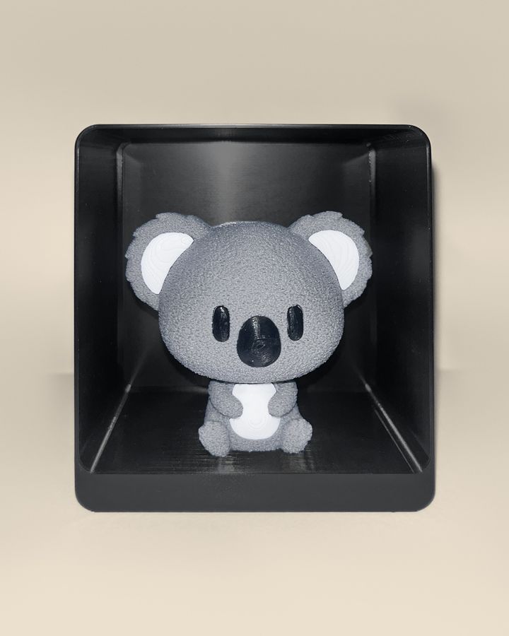 3D-printed koala figurine, front view: a grey koala with white ears and belly and a black nose