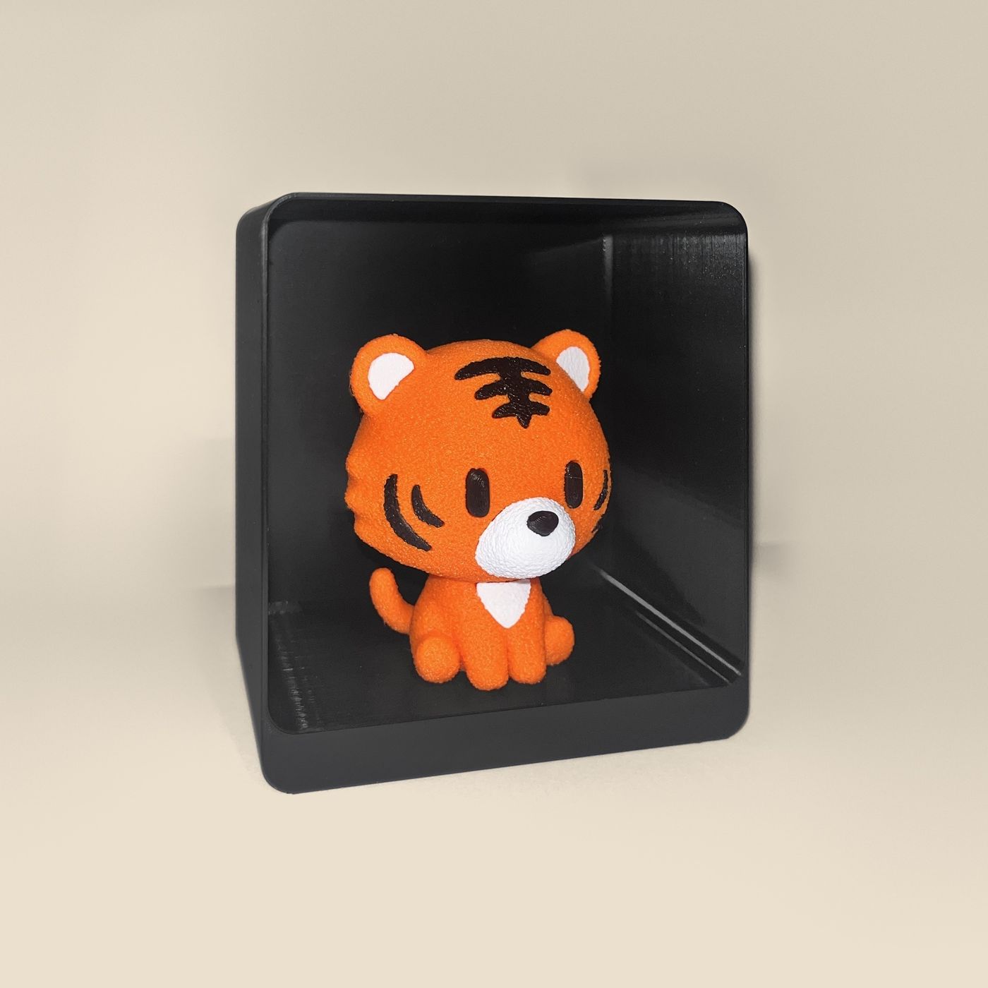 3D-printed tiger figurine, angled view: an orange tiger cub with black stripes and a white muzzle