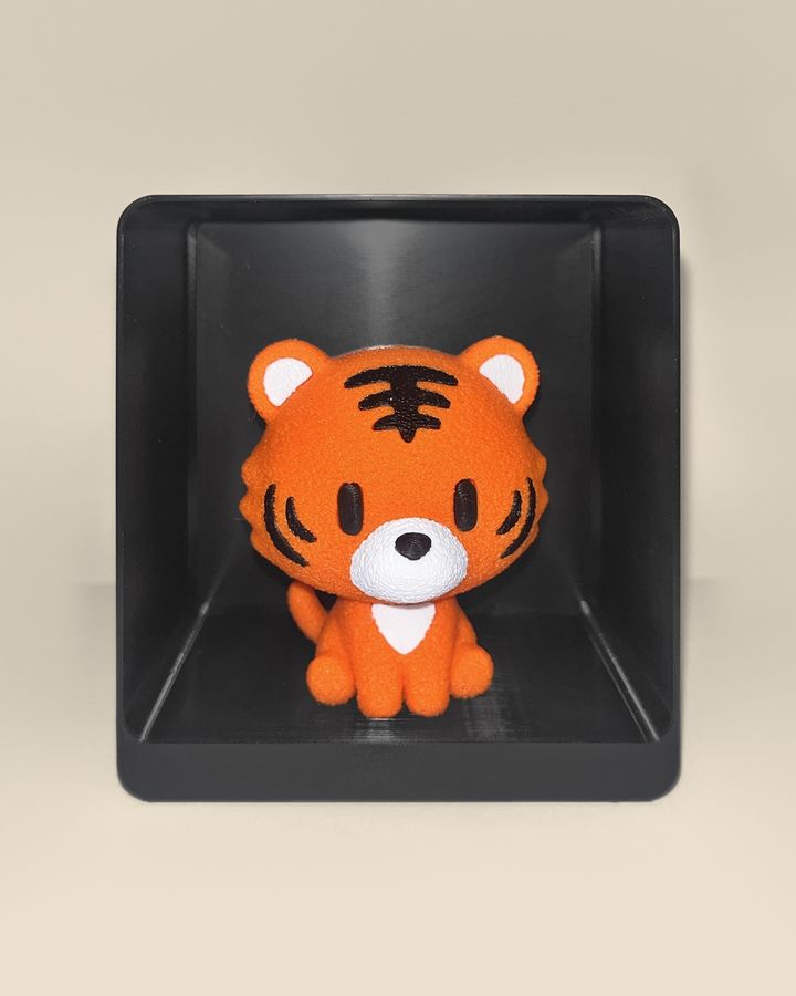 3D-printed tiger figurine, front view: an orange tiger cub with black stripes and a white muzzle